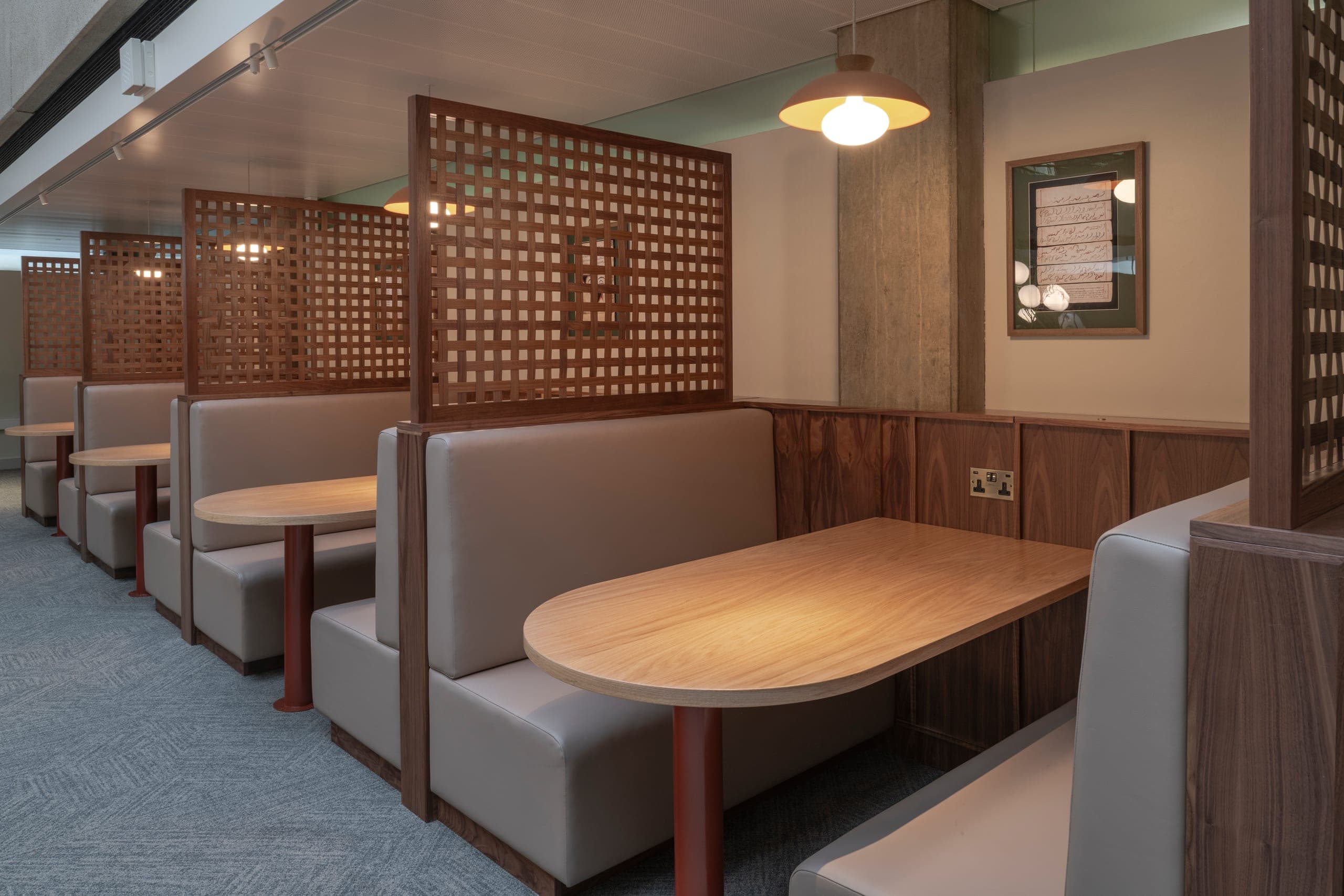 PIER banquette booths in a Cat B office fit-out — walnut lattice dividers with upholstered bench seating and timber tables