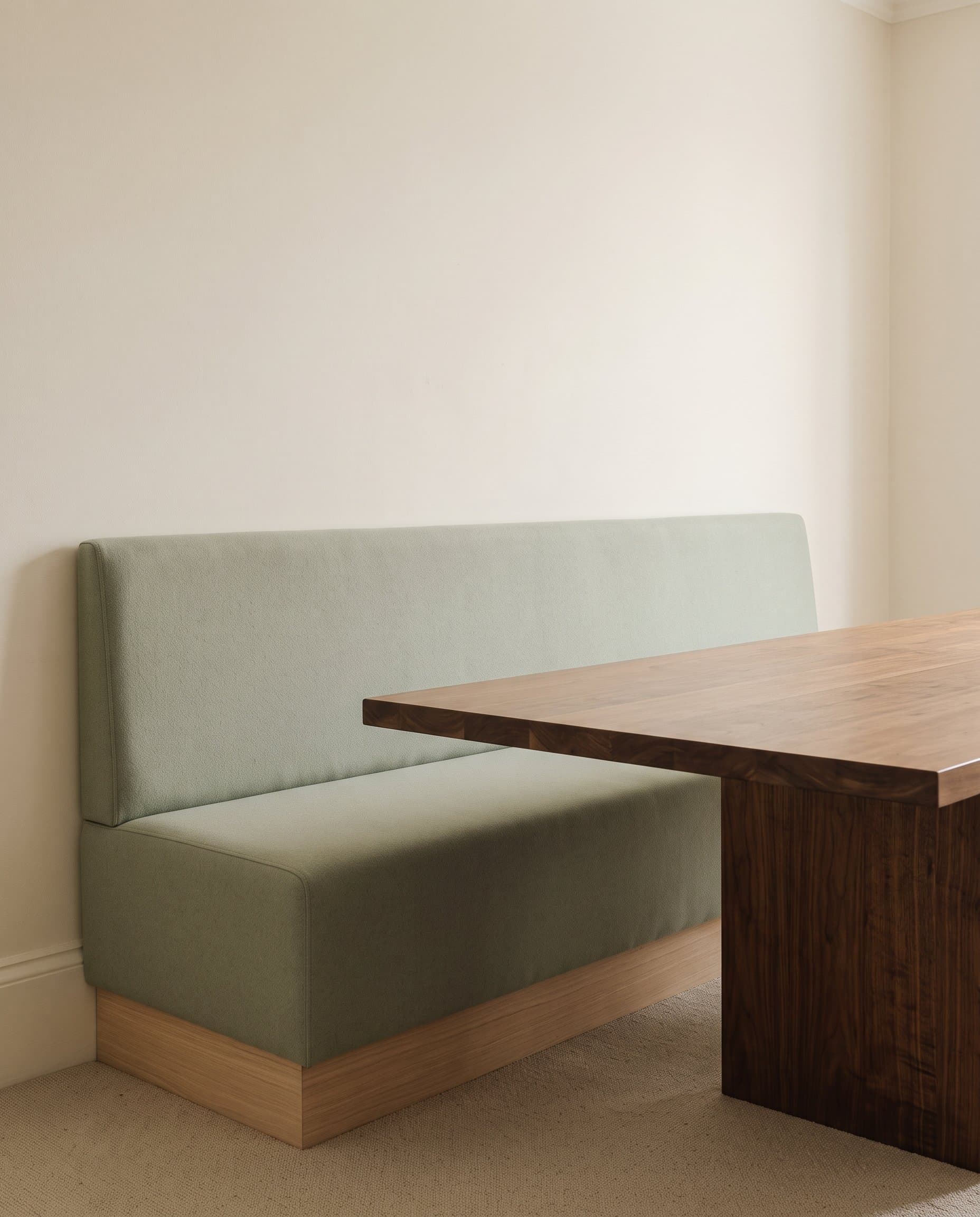 Salthouse: a plain-backed sage banquette on an oak kick plinth beside a walnut dining table