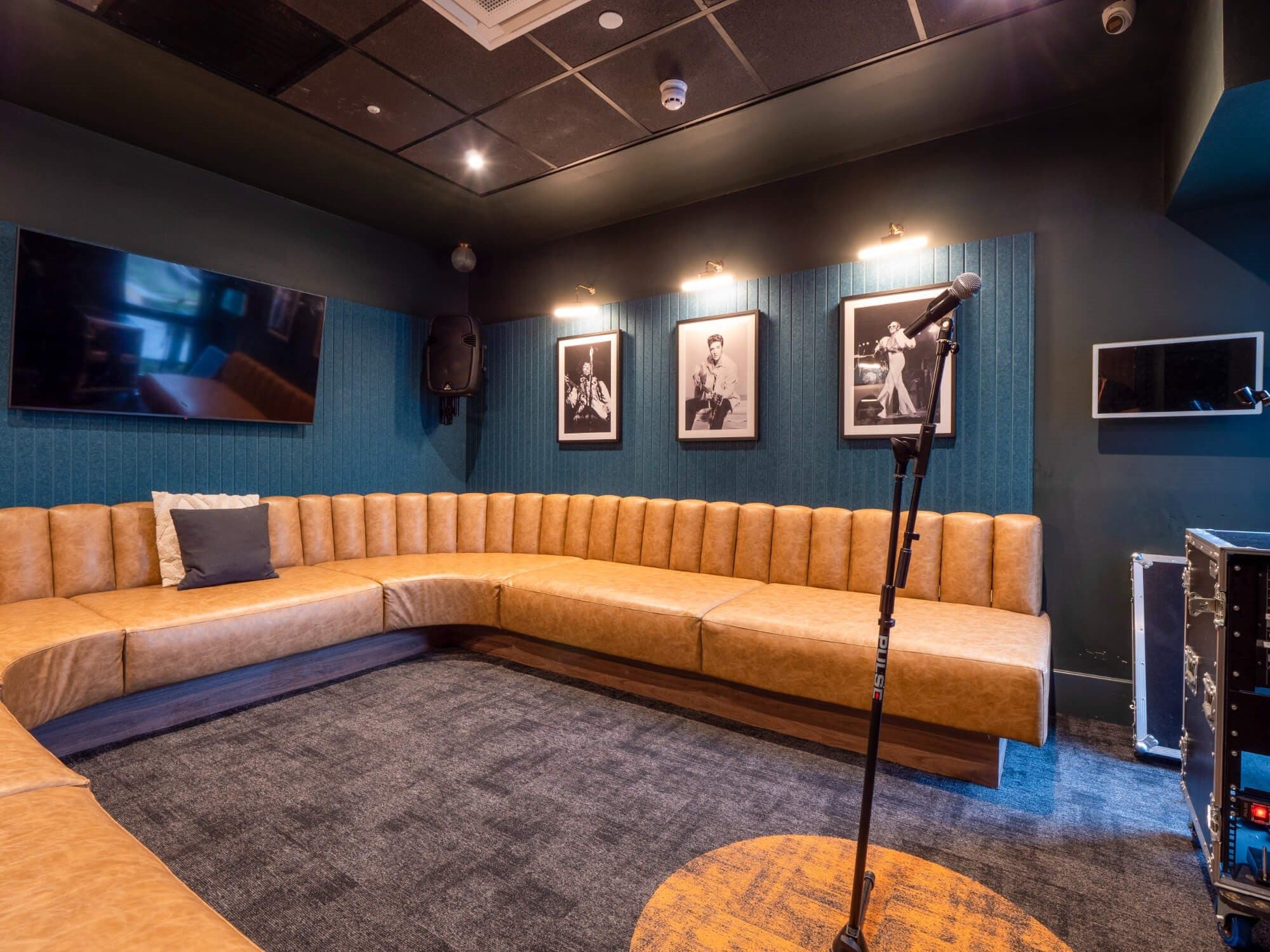 U-shaped fluted tan leather banquette wrapping a karaoke lounge with dark teal walls